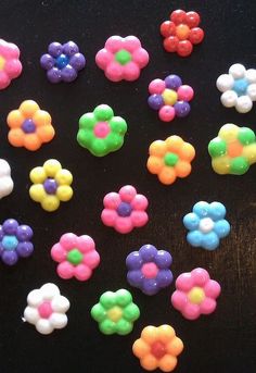 there are many different colored flowers on the black table top, and one is white