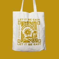 a white tote bag with the words let it be easy printed on it, against a yellow background