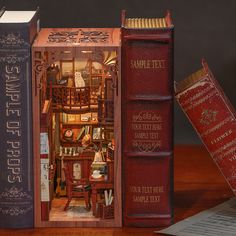 two books are opened to show the inside of a miniature house and it is sitting on a table