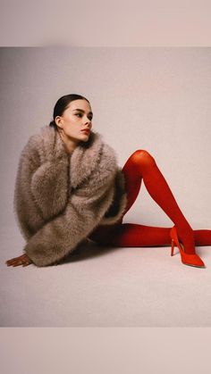 a woman in red stockings and high heels is sitting on the floor