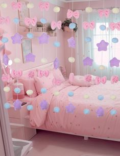 a bedroom decorated in pink and purple with stars hanging from the ceiling