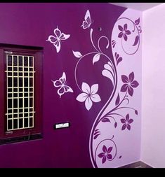 a purple wall with white flowers and butterflies painted on the wall next to a window