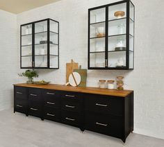 a kitchen with black cabinets and white brick walls