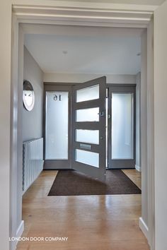 an open door leading into a room with wooden floors and white walls, in front of a clock