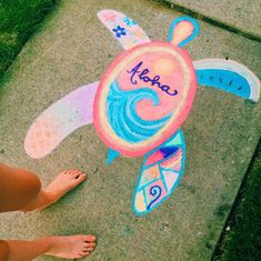 someone is standing on the sidewalk with their feet in front of a chalk drawing turtle