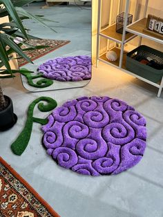 two purple rugs sitting on the floor next to a potted plant