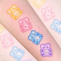 four different colored teddy bear tattoos on the arms and legs, all with circles around them