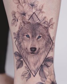 a close up of a person's leg with flowers and a wolf on it