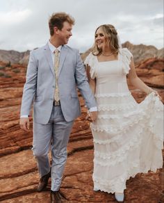 a man and woman are walking through the desert holding each other's hands as they smile