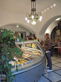 a woman standing in front of a display case filled with food