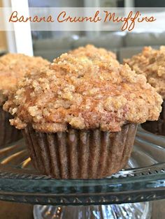 two muffins sitting on top of a glass cake plate with the words banana crumb muffins