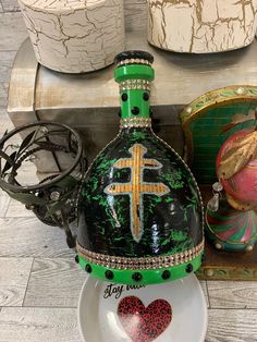 a green and white vase with a cross on it sitting on a plate next to other decorative items