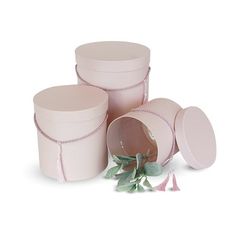 three pink round boxes with green leaves on the top and one has a white lid