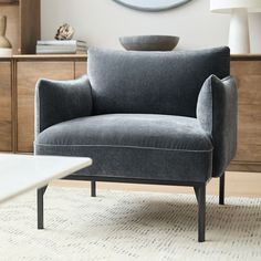 a gray chair sitting on top of a rug in front of a wooden dresser and mirror