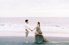 a man and woman holding hands on the beach