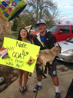 a man and woman holding up a sign with a goat