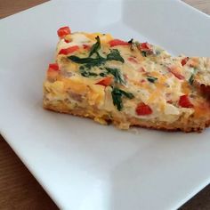 a slice of quiche on a white plate with cheese and vegetables in the middle