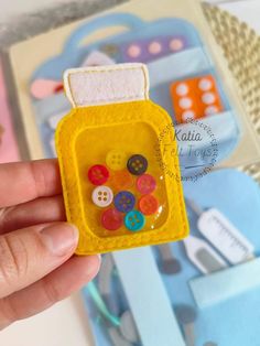 a person holding a small yellow case with buttons in it