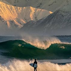 a man standing on top of a surfboard in front of a large ocean wave