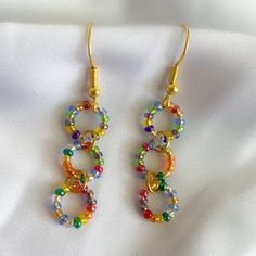 two pairs of colorful beaded earrings sitting on top of a white cloth