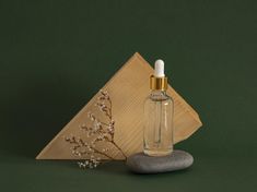 a small bottle with a gold cap sitting on top of a rock next to a wooden triangle