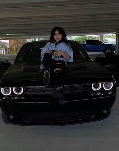 a woman sitting on the hood of a black car