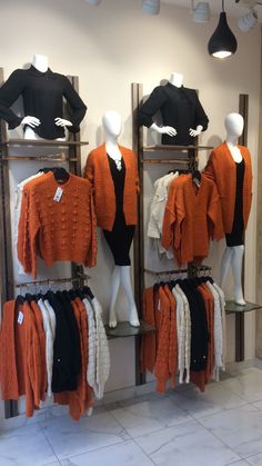 mannequins and sweaters are on display in a clothing store, including orange cardigans