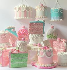 there are many different cakes on the table and one is pink, green, white and blue