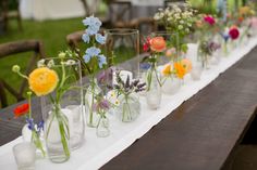 a long table with many vases filled with flowers