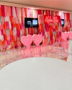 a room filled with lots of pink and orange chairs next to a wall covered in curtains