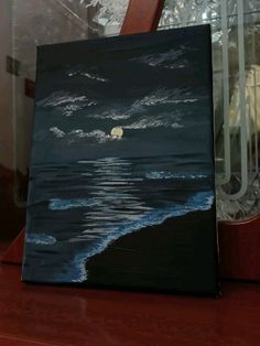 a painting on a table with a clock in the background and an ocean scene behind it