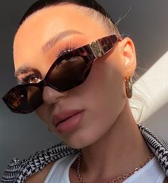 a woman with sunglasses on her head and an animal print scarf around her neck is posing for the camera