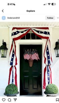 an american flag draped over the front door of a house with lanterns on either side