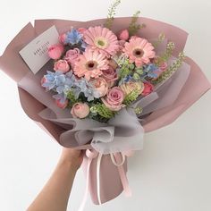 a person holding a bouquet of flowers in pink and blue colors on a white background