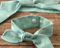 a light green bow tie with white polka dots on it sitting on top of a wooden table