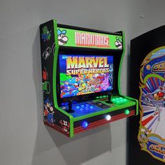 an arcade machine next to a wall mounted video game screen with the title'marvel superheros'on it