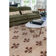 a living room with a couch, coffee table and rugs on the floor in front of a window