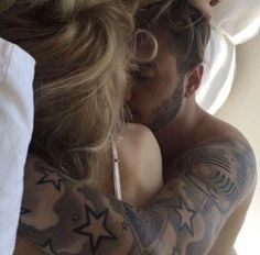 a man and woman embracing each other with tattoos on their arms