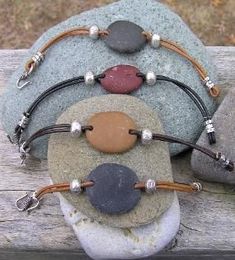 three bracelets with different colored stones and beads on them sitting on top of a rock