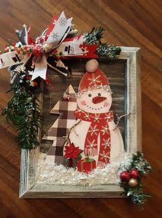 a wooden frame with a snowman and christmas decorations