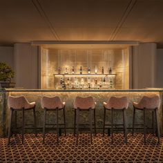 three bar stools in front of a counter with bottles on it