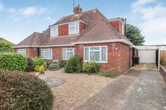 a brick house sitting next to a lush green hedge covered yard with trees in the background