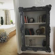 a book shelf with books on it next to a mirror in a room filled with furniture