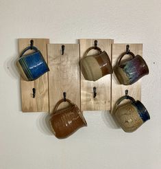 four teapots are hanging on the wall and one is made out of wood