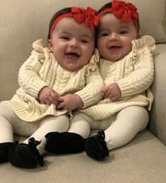 two babies are sitting on a couch with their arms around each other and smiling at the camera