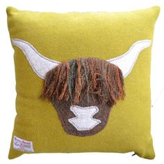 a yellow pillow with a brown and white bull's head embroidered on the front