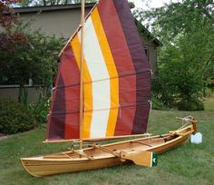 a sailboat sitting on the grass in front of a house