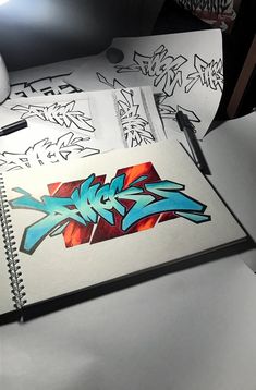 an open notebook with graffiti written on it next to a computer mouse and keyboard,