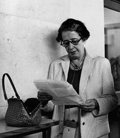 an old woman reading a newspaper next to a purse