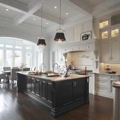 a large kitchen with an island in the middle and two pendant lights hanging from the ceiling